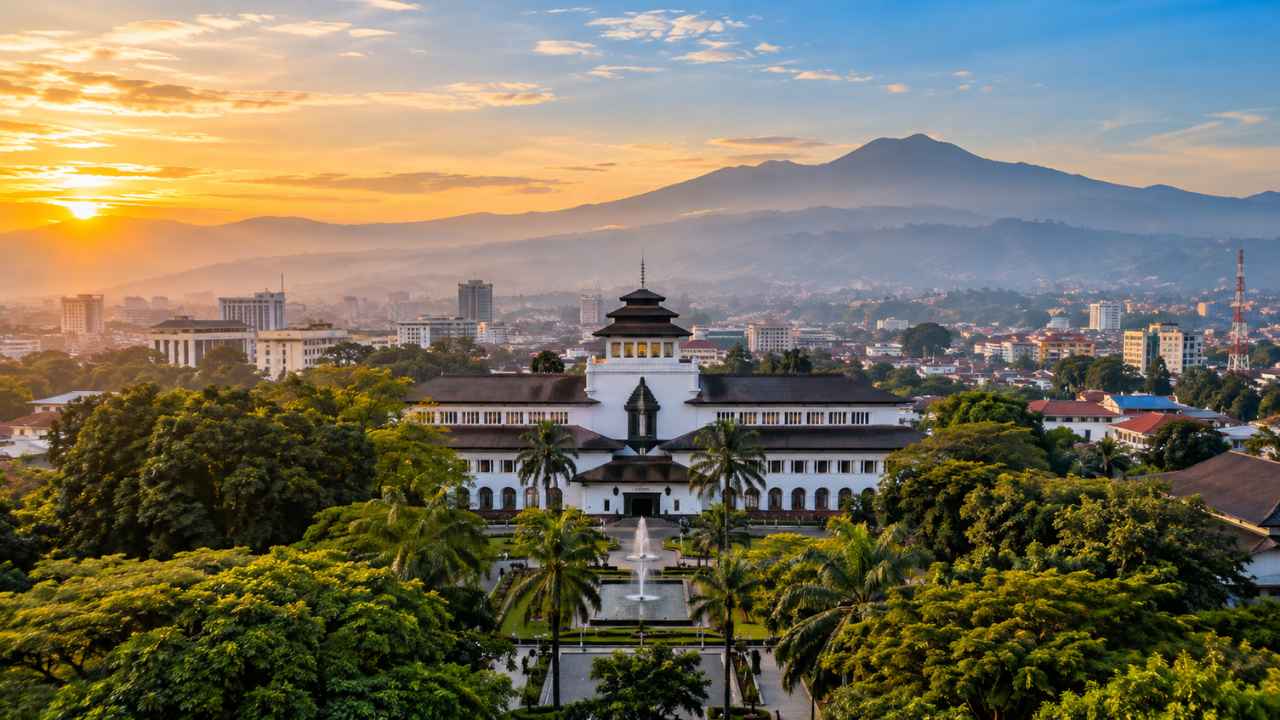 Gedung Sate Bandung dengan atap khas dan menara berujung ornamen, berlatar langit matahari terbit keemasan