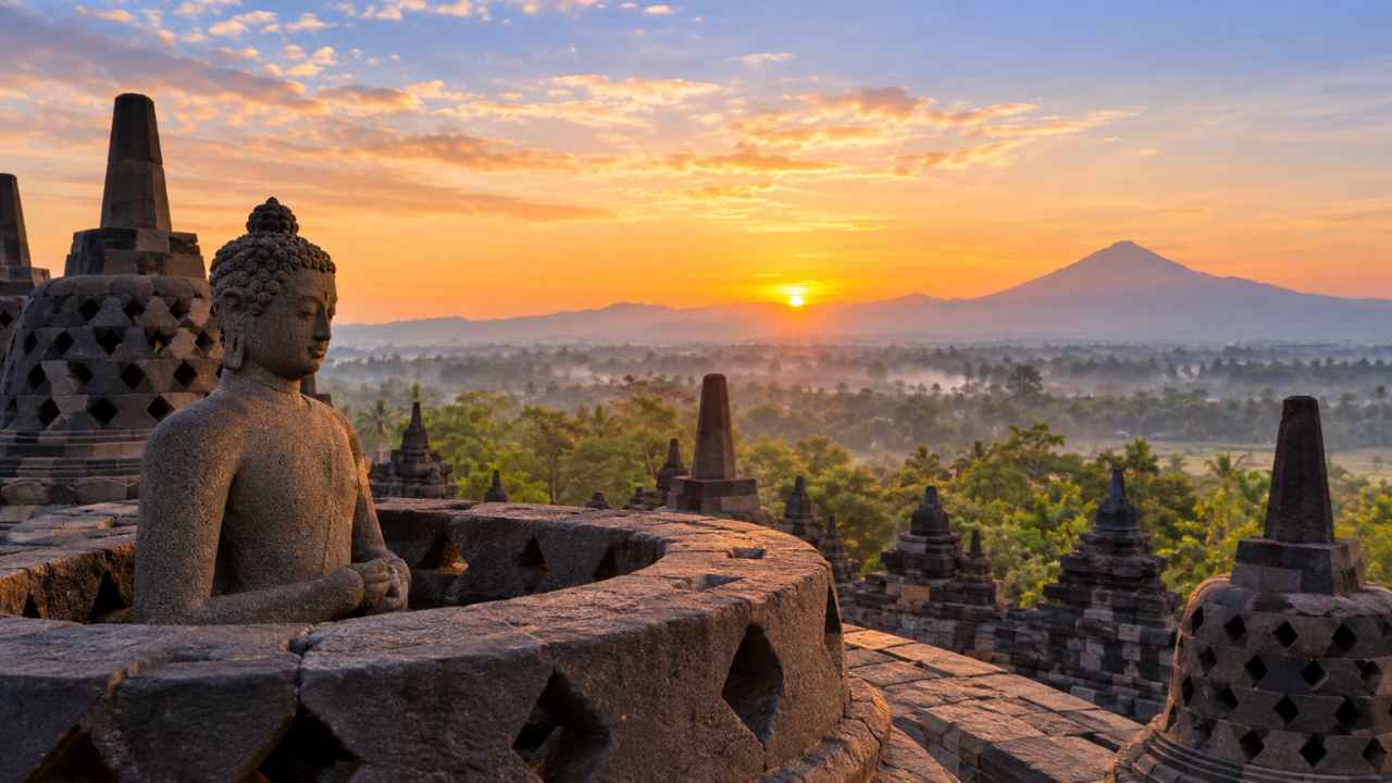 Matahari terbit di atas stupa Candi Borobudur dengan barisan candi dan perbukitan berkabut di kejauhan