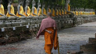 Monk walking around the statues of Buddha in Wat Yai Chaimongkol temple in Ayutthaya, Thailand